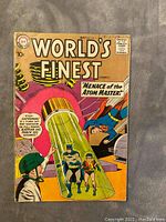 Front cover of World's Finest Comics #101 featuring Batman, Robin, and Superman in a scene titled 'Menace of the Atom Master!'