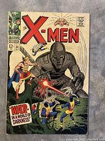Front cover of X-Men comic book #34 showing key characters and large robot in a fight scene with text 'WAR - IN A WORLD OF DARKNESS!'