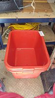 Large red plastic storage bin on floor showing size and condition
