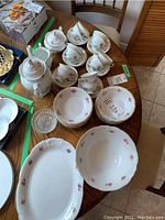 Wide view of Polish porcelain china set including platter, large bowl, soup bowls, tea cups, saucers, teapot, and sugar bowl on dining table.