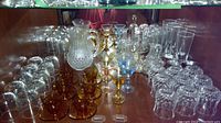 Full display of various glasses including amber espresso cups and clear crystal glasses on shelves.