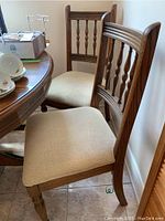 Two wooden dining chairs with upholstered beige seat cushions positioned next to a dining table.