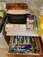 Photo of FoodSaver vacuum sealer, SeaMeal vacuum storage bags, Betty Crocker oven, glass cutting board, and cutlery drawer contents.