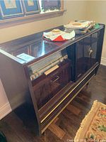 Full side view of vintage stereo cabinet with glass front and vinyl records on top.