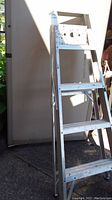 Front angled view of 4 ft aluminum step ladder showing step design and top platform with holes.