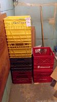 Stacked yellow, black, and red milk crates in a basement corner on concrete floor.
