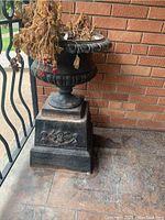 Front view of cast iron urn on square pedestal base