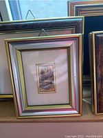 Framed miniature print with a silver border inside a wooden frame.