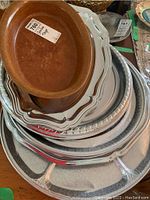 Stack of five plastic trays of different sizes and shapes, showing brown, white, and gray colors with various edge designs.