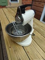 Photo of Sunbeam Mixmaster kitchen mixer with large stainless steel mixing bowl and two beaters on wooden deck.