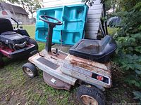 Left front angle photo of Univail 526 lawn tractor showing rusted metal body, black seat, front tires, and mower deck.