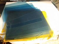 Blue translucent X-ray plastic copy sheets stacked on a white surface with yellow envelope underneath.