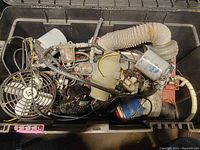 Tote filled with a variety of boat parts including tubing, fan, and filter canister shown from above.