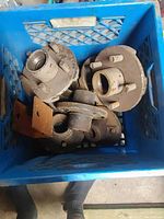 Blue crate filled with used trailer wheel hubs showing rust and dirt.