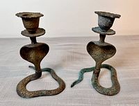 Pair of vintage brass candleholders shaped as snakes coiled on the base, showing patina and wear.