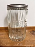 Front view of the glass coffee canister, showing vertical ridges and embossed word 'COFFEE'.