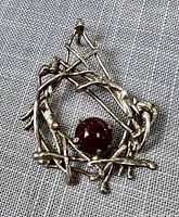 Front view of the pendant showing the intricate silver-tone modernist frame and central round Baltic amber stone.