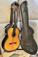 Open hardshell case containing full view of Takamine classical guitar