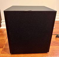 Front view showing black mesh cloth grille with slight tear at top edge