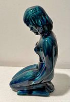 Side view of glazed Blue Mountain pottery figure with shiny blue-green glaze