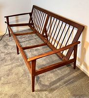 Photo of vintage mid century wooden sofa frame showing angled legs, armrests and spindle backrest design.