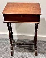 Front view of the vintage wooden box on carved stand showing the top as a flat panel and turned legs with stretcher connecting base supports.