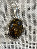 Front close-up of the amber pendant set in sterling silver with natural inclusions visible.