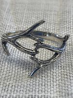 Close-up image of 925 sterling silver ring with an antler design on a textured fabric background.