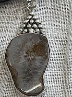 Close-up of irregularly shaped agate geode pendant with natural crystal formations set in 925 sterling silver plate.