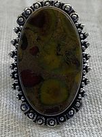 Front view of the oval fruit jasper gemstone ring showing jasper's natural coloration and decorative silver-tone setting.