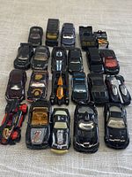 Top-down view of 22 black die-cast toy cars arranged in rows showing various designs and brands.