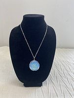 Full view of the black velvet stand displaying the opalite rose pendant on silver tone chain.
