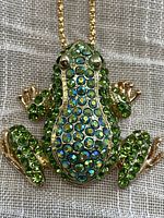 Front view of the gold tone frog pendant necklace showing multicolored green and blue faceted rhinestones covering the body and limbs.