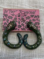 Front view of Betsey Johnson snake earrings with green enamel and rhinestone detailing on leopard print branded packaging