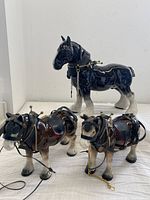 Set of three ceramic Clydesdale figurines with detailed leather and metal tack, showing all items in the lot