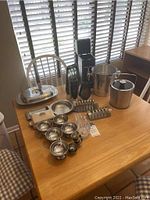 Wide view of barware and serveware items on table to show entire lot.
