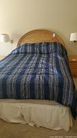 Front view of queen size bed with wood headboard and blue striped comforter.