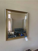 Front view of the gold framed beveled wall mirror reflecting a living room