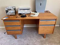 Full view of Mid-Century Modern wooden desk with items on top and drawer units on both sides.