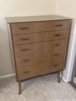 Front view of the dresser showing five drawers with wooden handles and MCM legs.