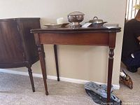 Full view of vintage wood table showing turned legs, rectangular top with scalloped edge, and polished dark wood finish.