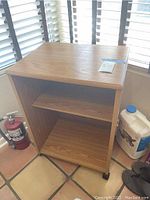 Wood rolling cabinet front view showing two shelves and natural wood finish with scratches.