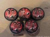 Five McDonald's 2002 Team Canada hockey pucks with player portraits and signatures.