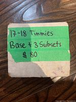 Closed cardboard box with green tape labeling '17-18 Timmies Base + 3 Subsets $80'
