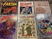 Top-down view of all six graphic novels bagged and boarded showing colorful covers