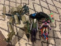 Full view of assembled lot items on carpet including Joker figure, mech suit, motorcycle accessory, and other figures.