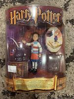 Front view of sealed Harry Potter Ginny Weasley figurine playset with accessories inside packaging.