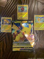 Four Pokemon cards displayed including Jumbo Pikachu V and three reverse holo Lightning-type cards Pikachu, Voltorb, Zapdos.