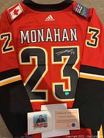 Back view of red Adidas Calgary Flames jersey showing ‘MONAHAN’ and signed ‘23’ with holographic sticker