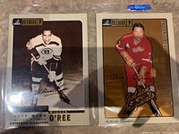 Both signed Pinnacle Beehive hockey cards of Willie O'Ree and Ted Lindsay shown side by side in protective sleeves.